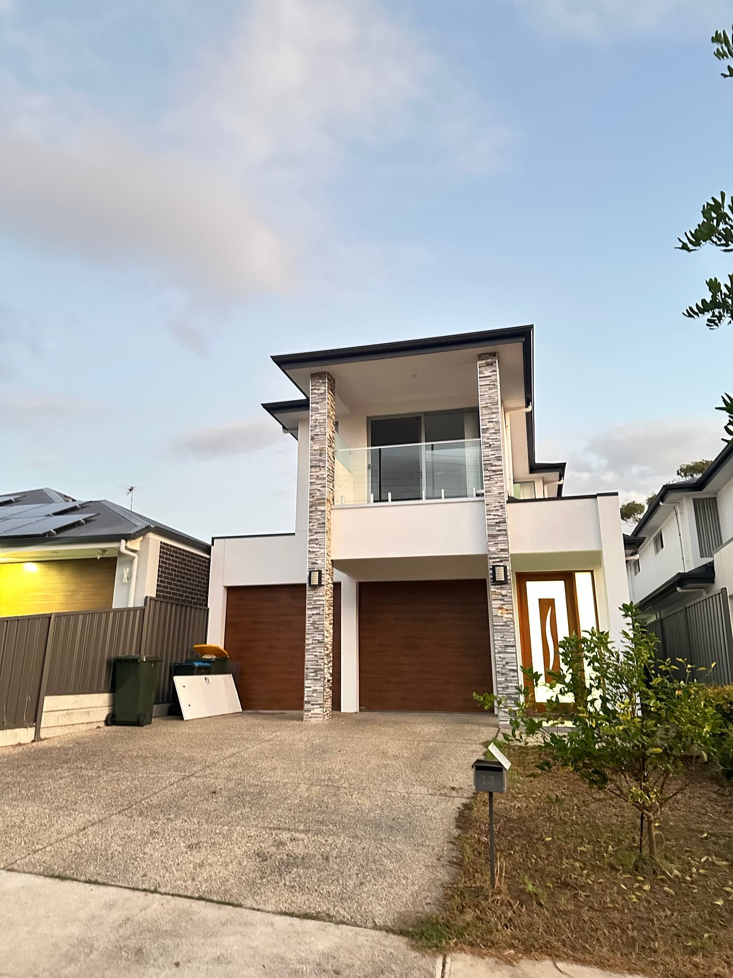 Contemporary double-storey home with stone columns and timber garage doors